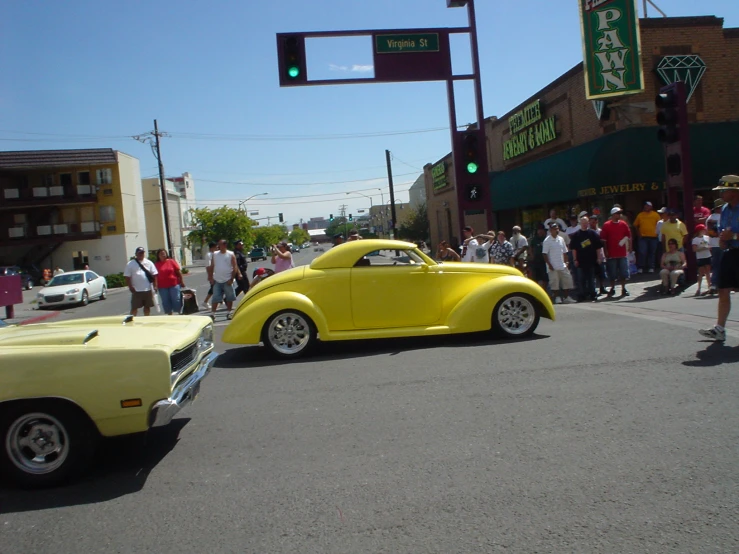 a yellow car parked near a crowd on the road