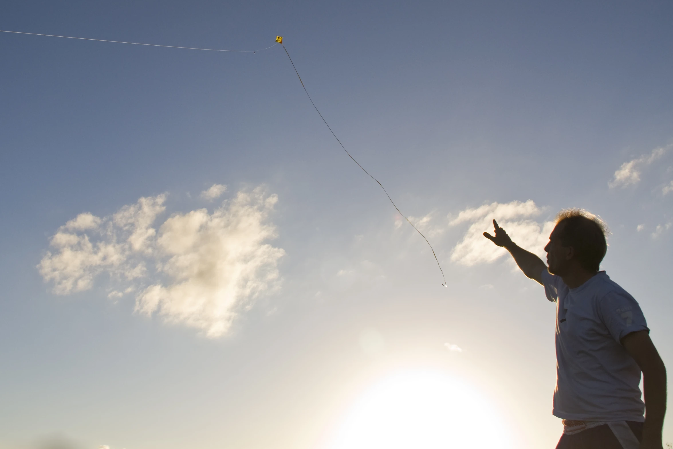 a man flying a kite on the sunlit day