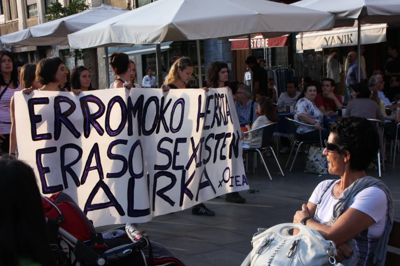 a person sitting on a bench holding a large protest sign