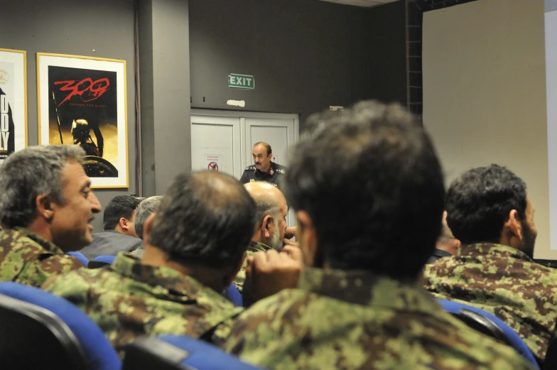 a man speaking to military personnel in a room