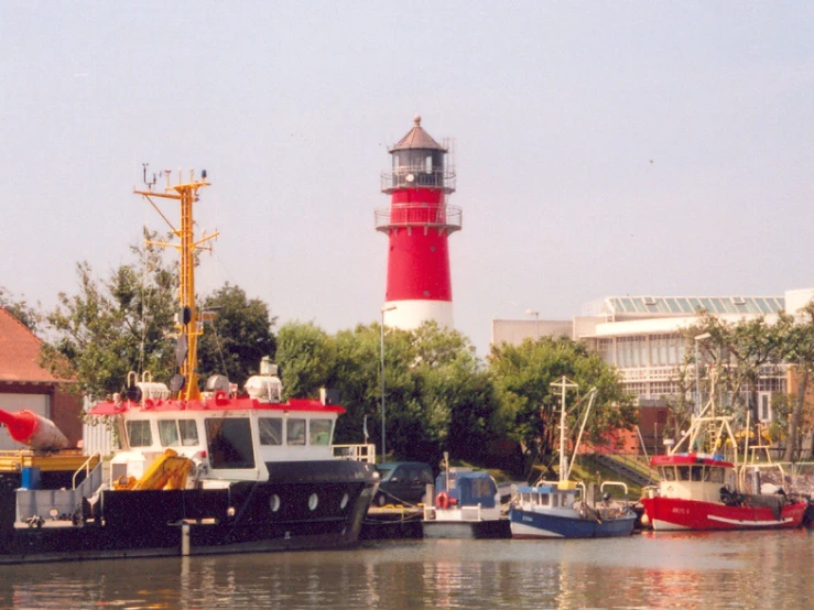 boats at a dock in front of a red and white lighthouse