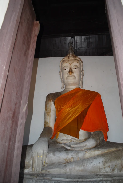 a buddha statue with orange cloth dd over it