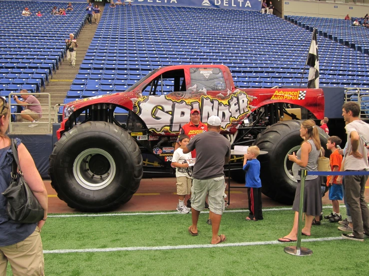 monster trucks are parked on the field near spectators