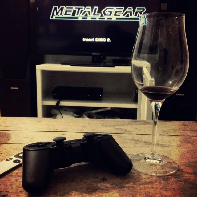 a glass and controller on a table near a television