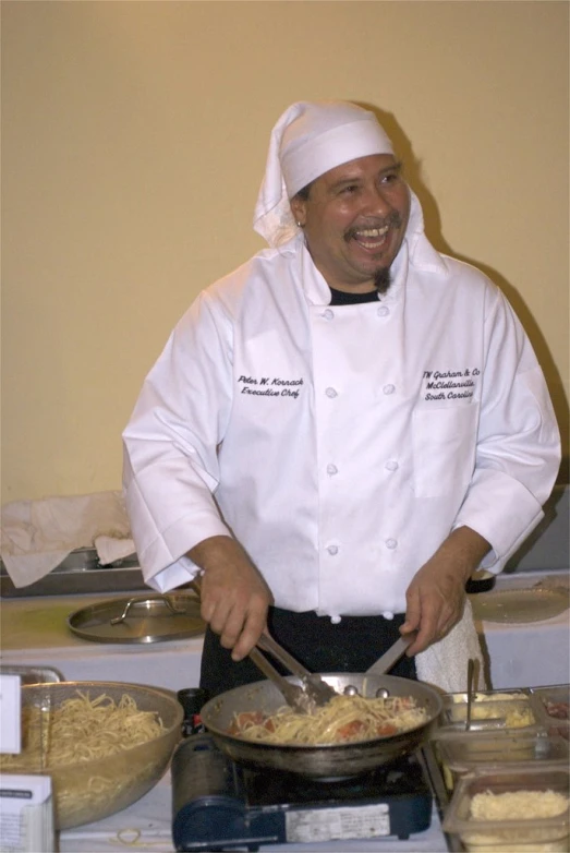 a chef wearing white prepares food in front of a table