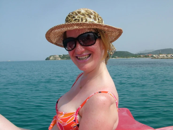 a woman in a bikini and hat on a boat