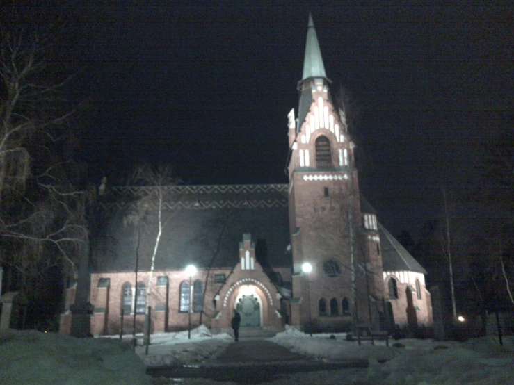 a large church lit up at night with snow on the ground