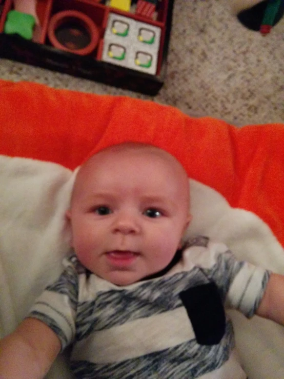 a baby is sitting in an orange chair with his head resting on a blanket