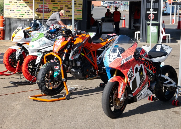 two motorcycles are parked on the pavement by some people