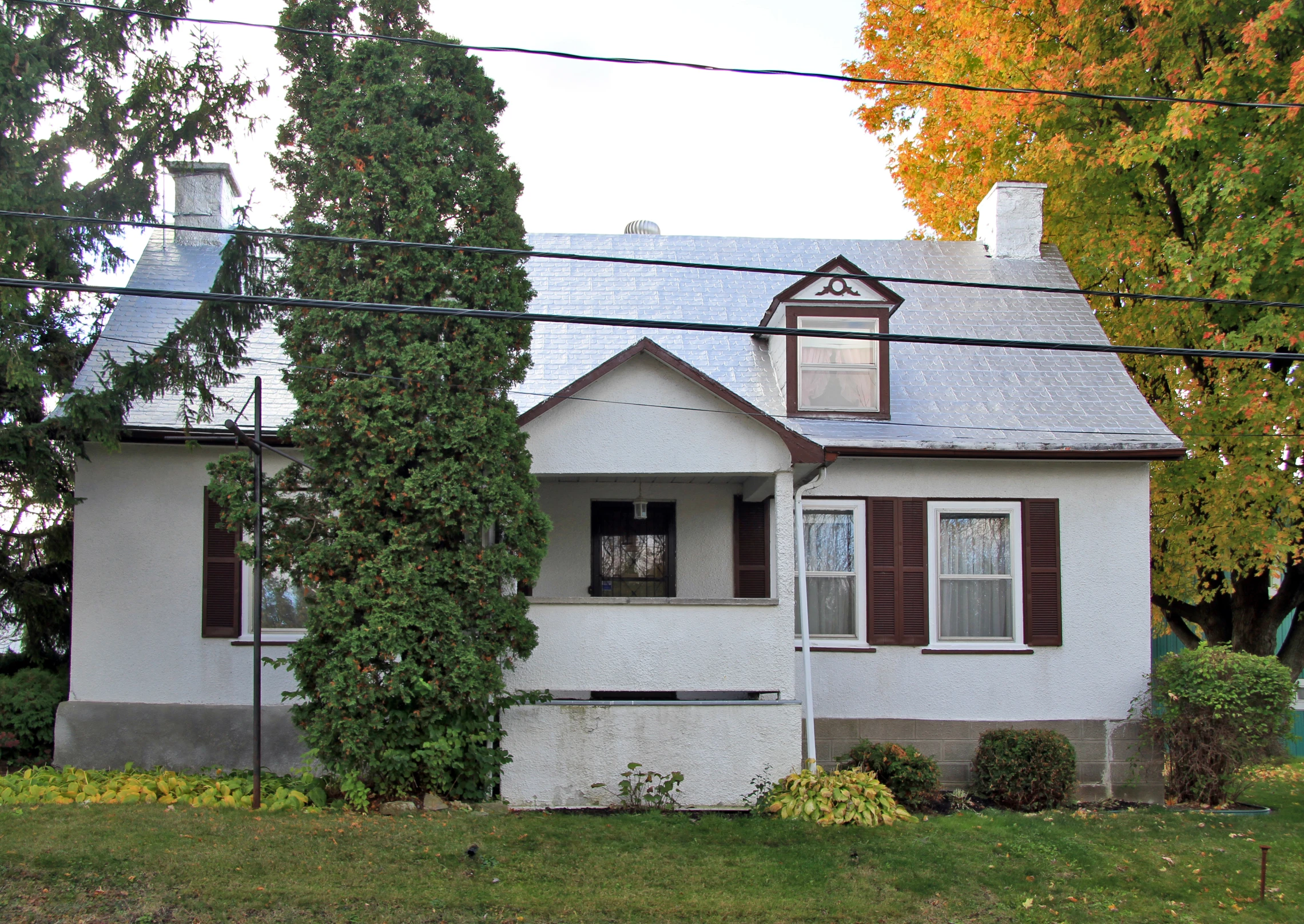 an old white house with a few brown shutters