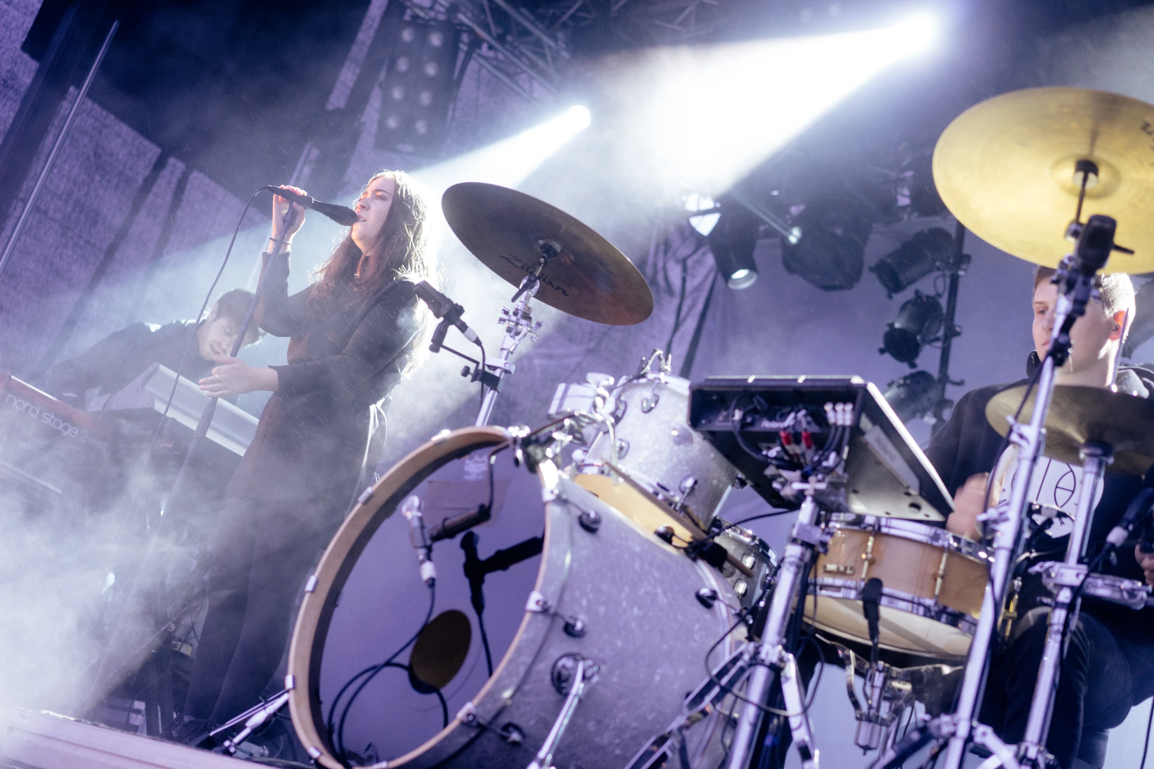 a man holding a microphone next to drums on stage