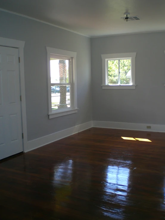 an empty room with three windows and a hard wood floor