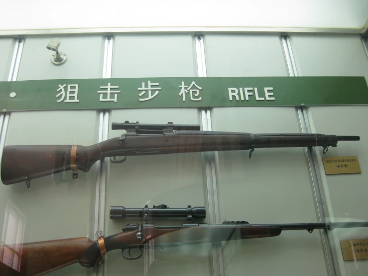 two guns displayed behind glass in front of a window
