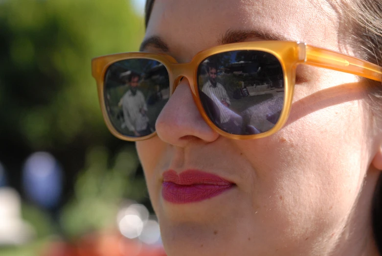 a woman wearing yellow sunglasses with her head tilted