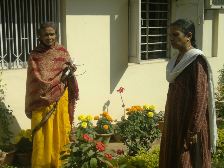 two women standing around with a umbrella on the side of a house