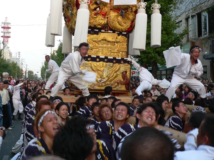 several men and women doing stunts in the street in front of a large float
