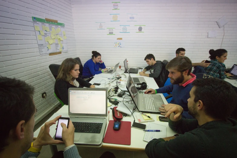 there are a group of people sitting around a table using computers