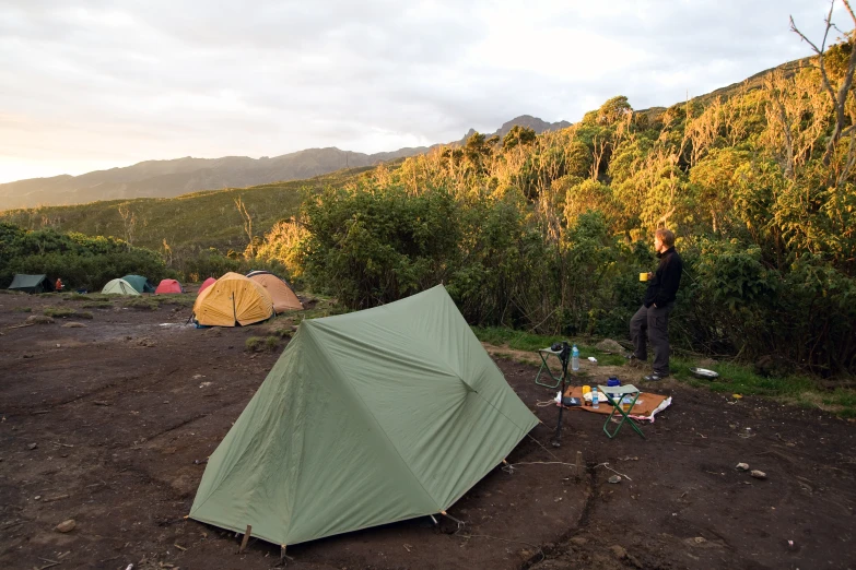 the man is standing next to a tent in a field