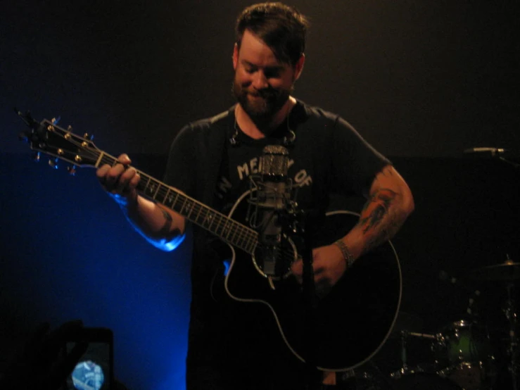 a man is holding a guitar and looking at the camera