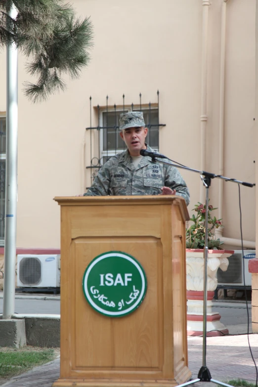 the soldier is speaking at the podium outside