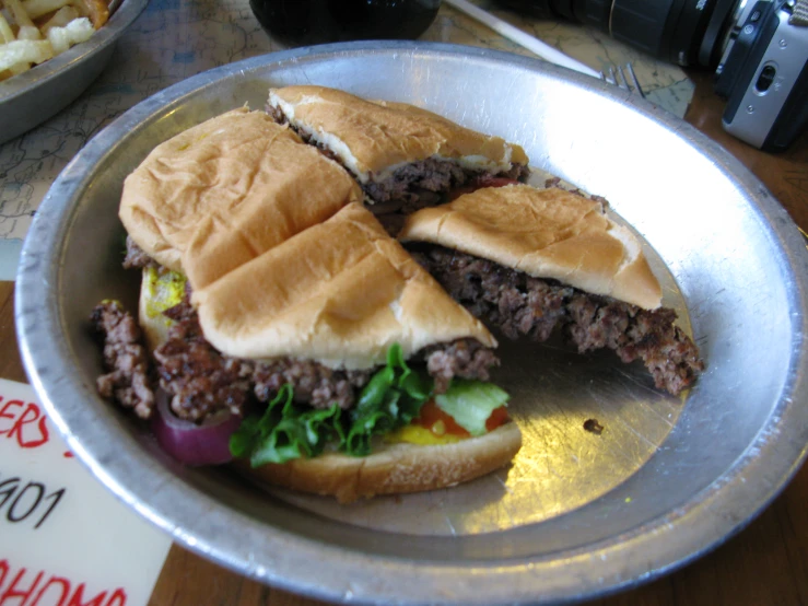 a large meat sandwich with fries on a table