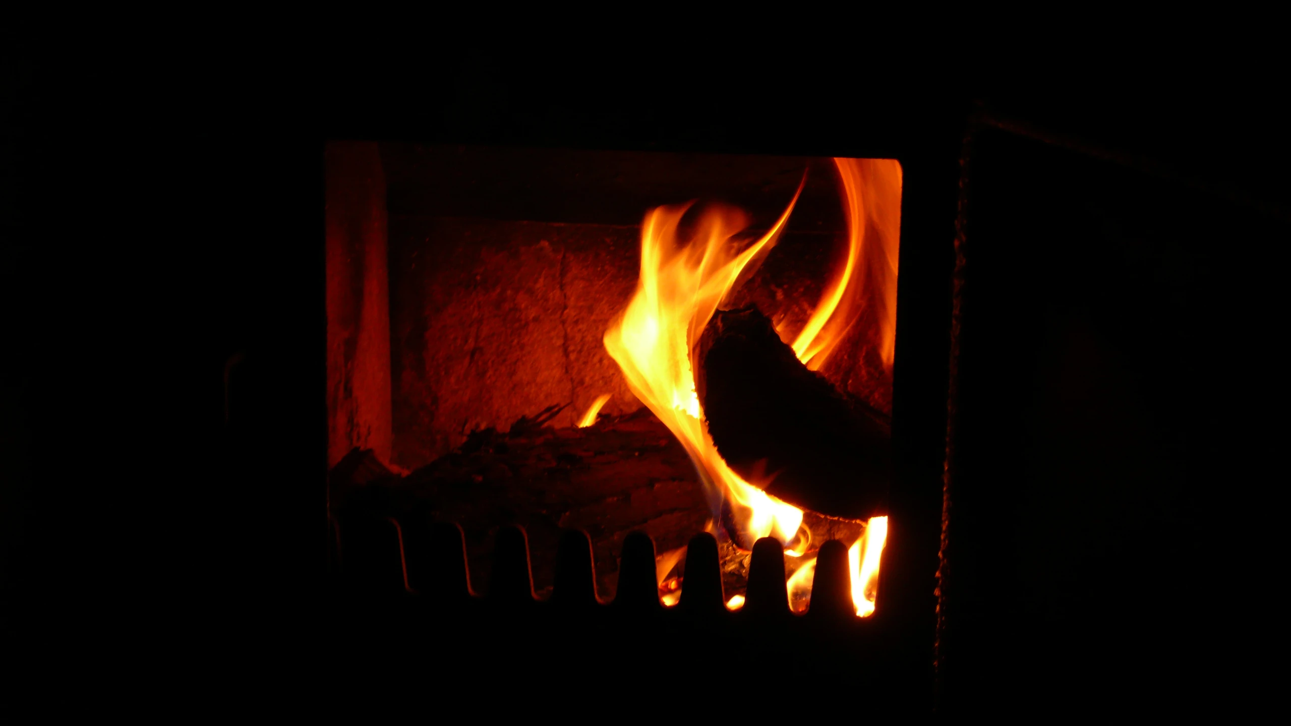 a wood fire burns in a dark room