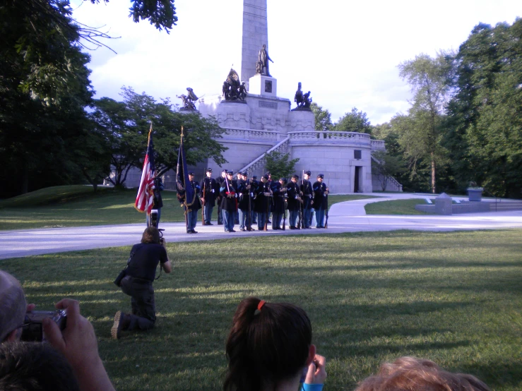 some people standing in a park near an american flag