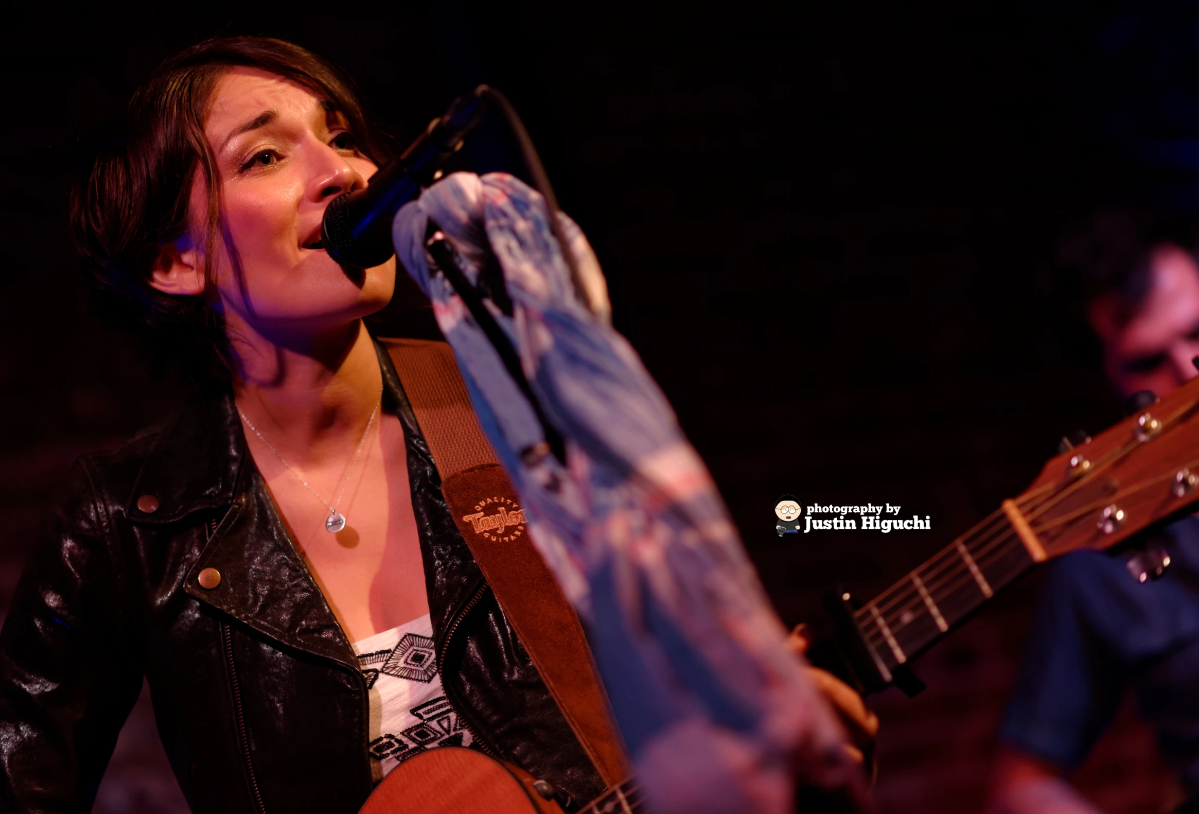 a woman singing and playing a guitar at night