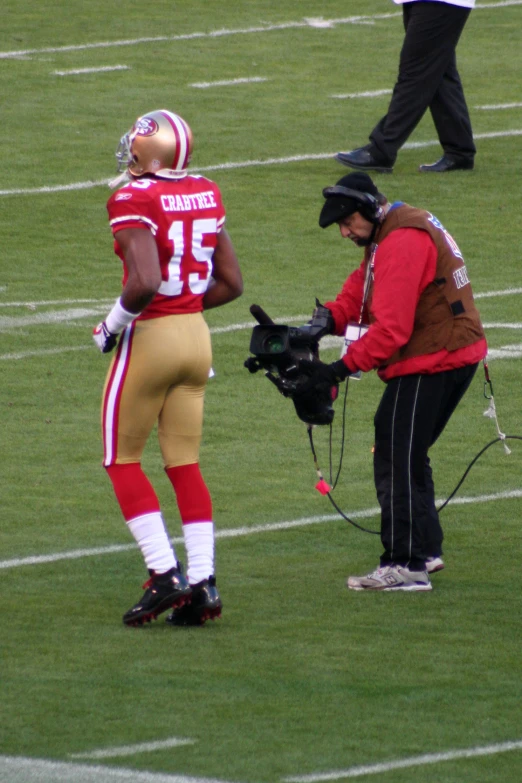 a football player stands next to a cameraman