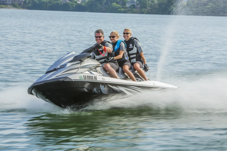 three people riding on the back of a jet ski