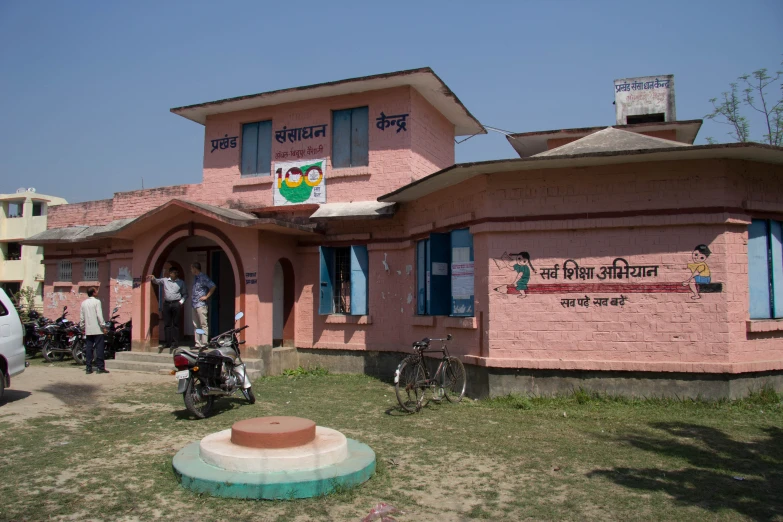 a pink brick building sitting on top of a lush green field