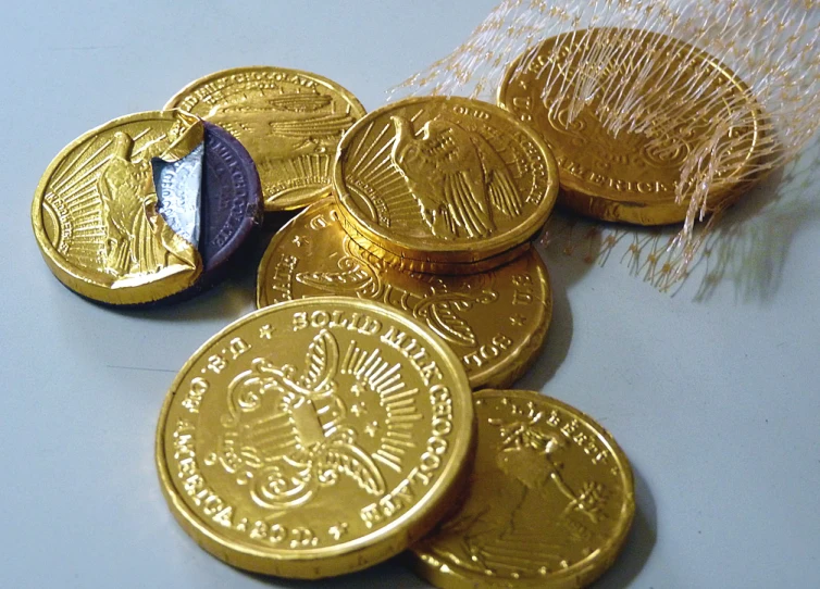 a pile of four golden coins sitting on top of a table