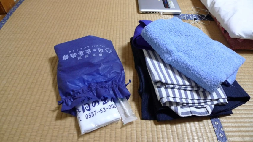 there is a blue towel and some folded towels on top of the bed