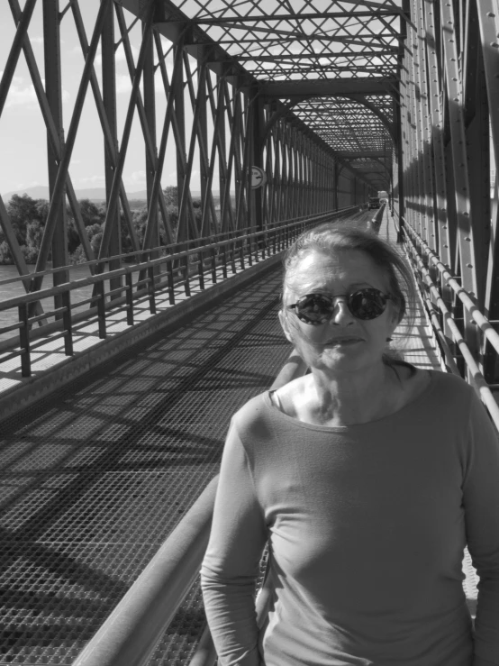 a woman standing on a bridge with her sunglasses on