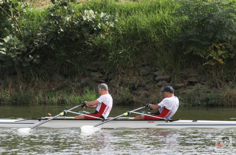 two men rowing down the river on their boat