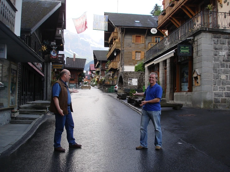 two men standing on an old street next to buildings