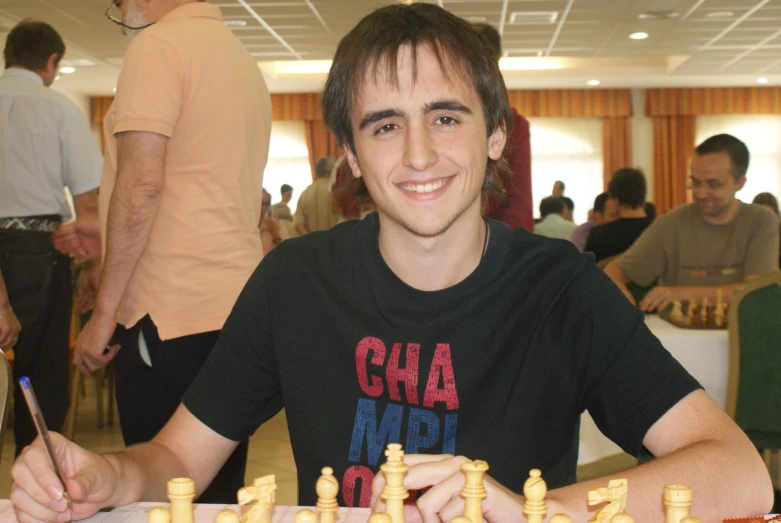 a man sitting at a table with a chess board and pens