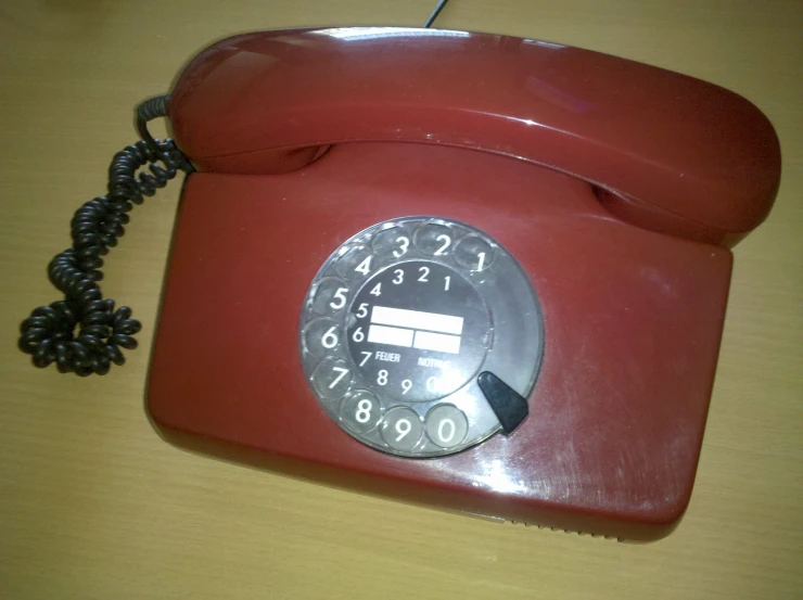 a red phone on a table with a cord on it