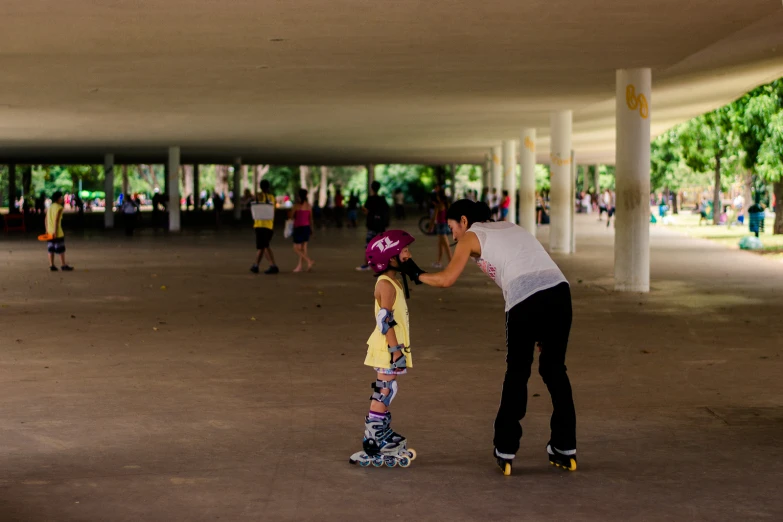 two people standing in an indoor area with one riding on a skateboard