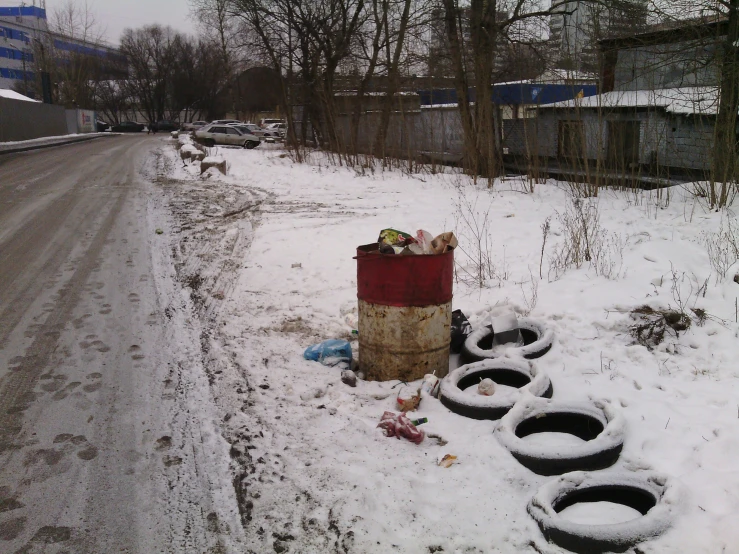 snow covers the ground in front of a tire trailer with a pile of dirty tires around it