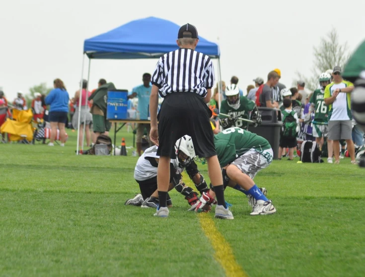 some soccer players playing in a game and some blue and white tents