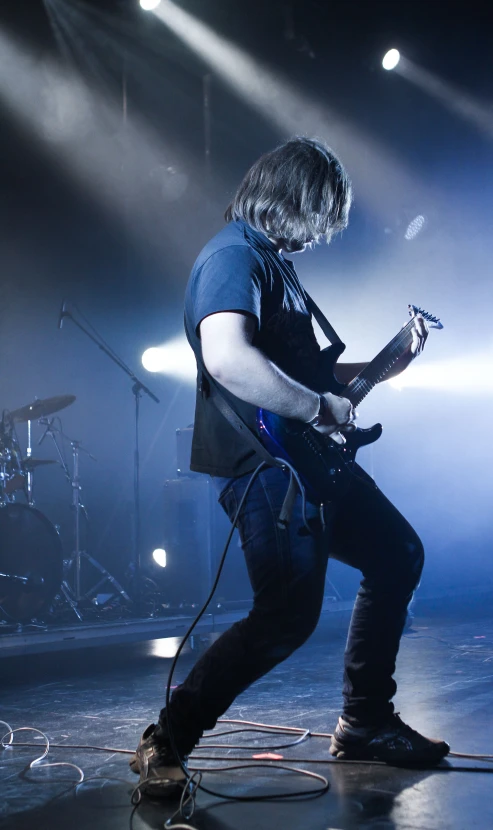 guitarist performing on stage at a concert with lights streaming overhead