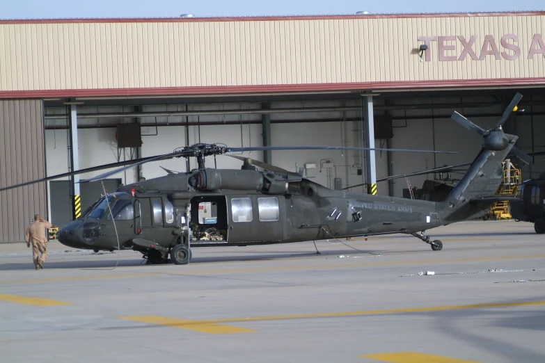 the black helicopter is parked next to an airplane hangar