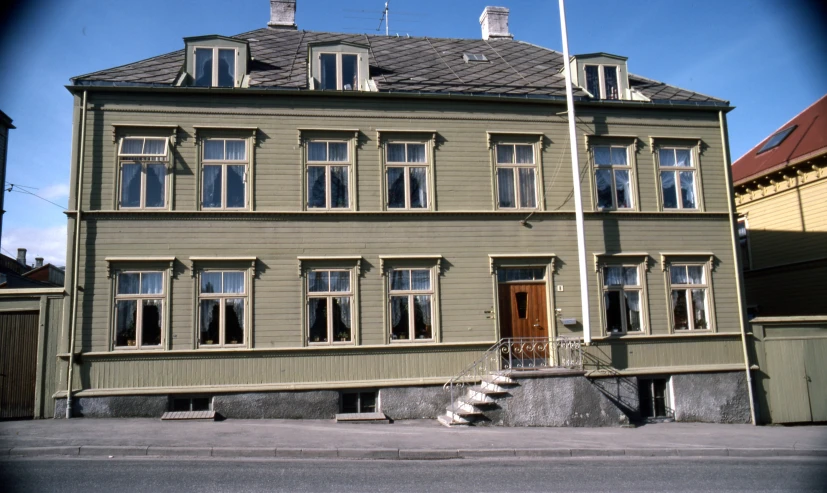 a grey and black clock is in front of a large brown building