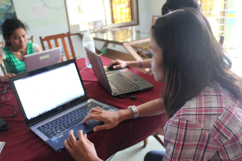 two people sitting at a table with laptops