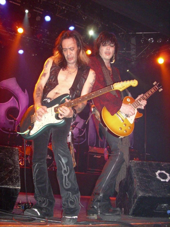 two men standing in front of a microphone holding guitars