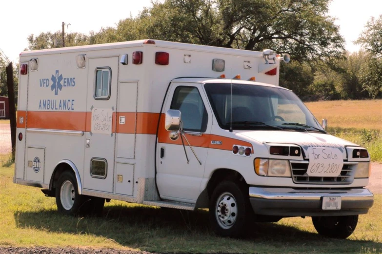 an ambulance is parked in the grass near a road