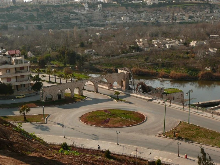 an empty roadway surrounded by grass, dirt and buildings