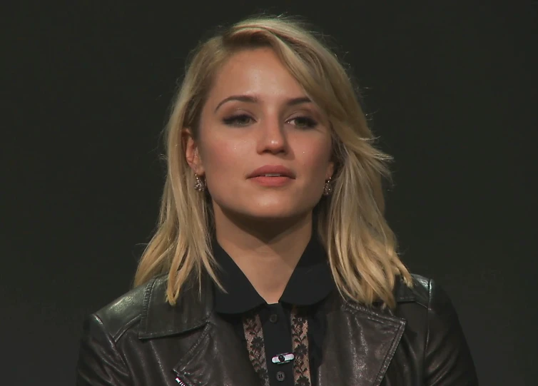 a woman with blonde hair, wearing a leather jacket