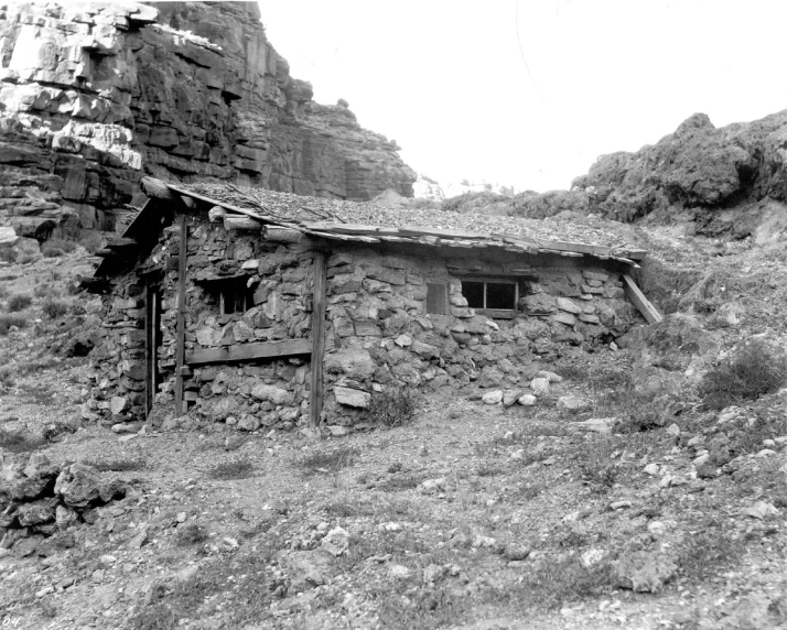 an old rock and wood building in the mountains